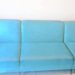 ספה כחולה נקייה עם כריות ישיבה ומשענות ידיים.