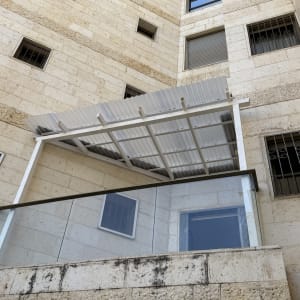 מרפסת עם סוכך מתכת על בניין אבן
