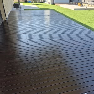 דק עץ בגינה עם דשא סינתטי וכיסאות פלסטיק