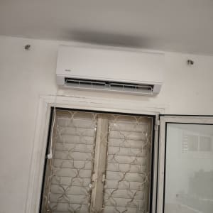 מזגן מותקן מעל חלון עם סורגים