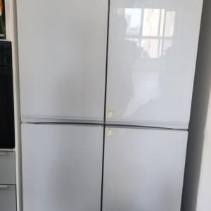 מקרר לבן עם דלתות סגורות ומקל מטאטא