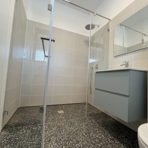 מקלחת עם דלת זכוכית, ארון כיור ומראה