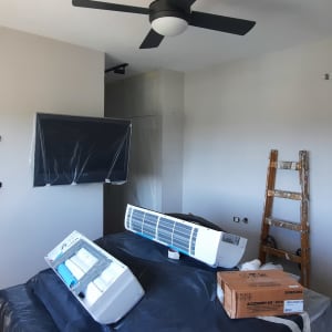 חדר בשיפוץ עם סולם, מזגן וקרטון על הרצפה