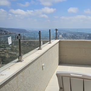 מרפסת עם מעקה זכוכית ונוף לעיר