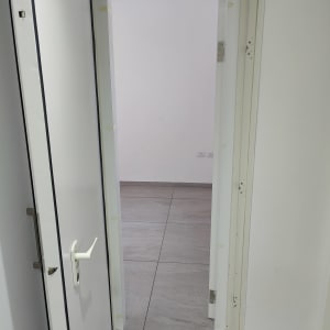 דלת לבנה פתוחה עם ידית לבנה וחלקי צירים