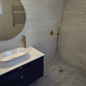 חדר אמבטיה עם כיור, מקלחת וברזים מוזהבים