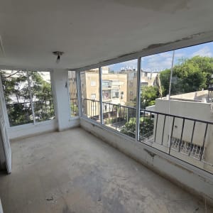מרפסת סגורה עם חלונות גדולים ונוף עירוני