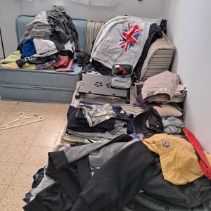 בגדים מקופלים ומפוזרים על ספה, קולבים על הרצפה