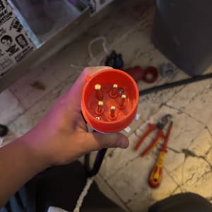 יד מחזיקה תקע חשמלי עם כלים ברקע