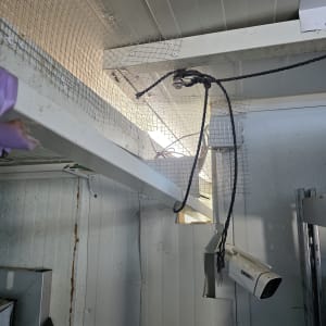 מצלמת אבטחה מותקנת על קיר עם רשת מתכת