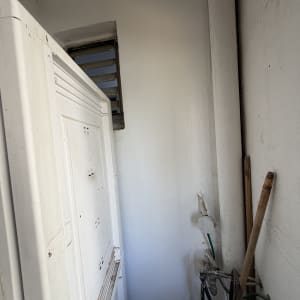 קיר שנצבע מחדש בצבע לבן בנישת שירות ליד צנרת