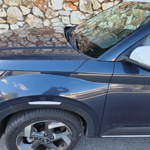 תמונה של רכב כחול עם קיר אבן ברקע