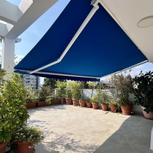 מרפסת עם סוכך כחול וצמחייה מסביב