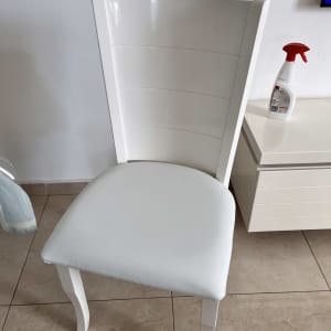 כיסא מרופד לבן ליד שידה עם תרסיס ניקוי
