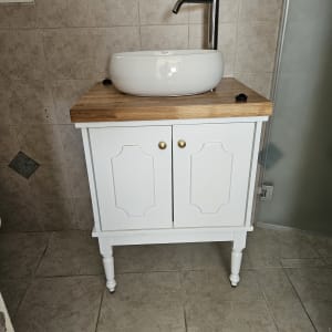 כיור עגול על ארון עץ לבן עם ברז מתכת