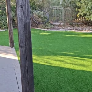 התקנת דשא סינטטי בחצר בית פרטי לצד מרפסת מרוצפת
