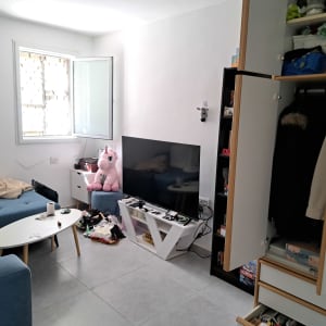 חדר מסודר עם ספה, טלוויזיה וארון פתוח