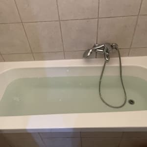 אמבטיה עם מים וברז מתכת על קיר מרוצף