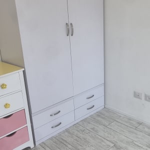 ארון לבן עם ידיות מתכת על רצפת עץ אפורה