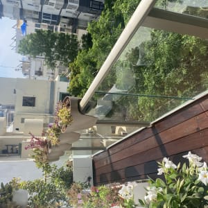 עציצים עם פרחים על מעקה זכוכית במרפסת עץ