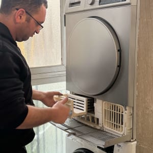 אדם מתקן מכונת כביסה עם מייבש