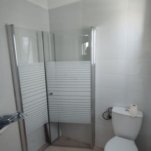 מקלחון זכוכית עם דלתות מתכת בחדר אמבטיה