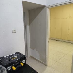 עבודת החלקת קיר בשפכטל לצד ארגז כלים של צבעי