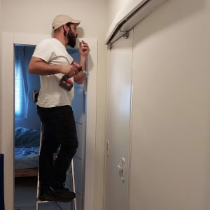 אדם על סולם מתקין מנעול על דלת