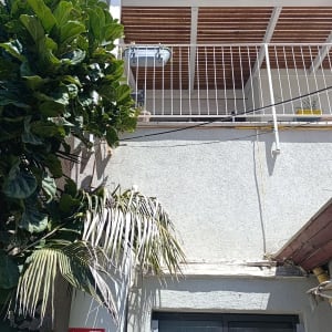 מרפסת עם מעקה לבן וצמחייה ירוקה