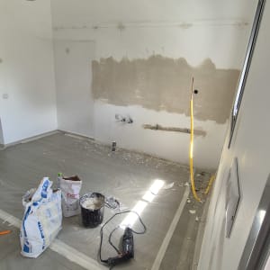 חדר עם קיר צבוע חלקית, דלי צבע וכלי עבודה