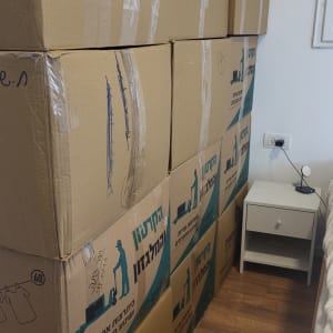 קופסאות קרטון מסודרות ליד מיטה בחדר