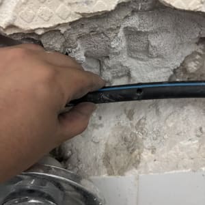 יד מחזיקה צינור ליד קיר שבור