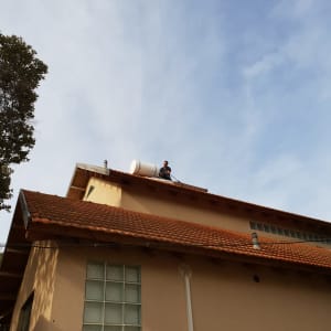 אדם מתקין דוד שמש על גג רעפים