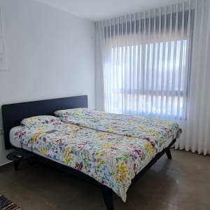 וילון לבן שקוף תלוי על חלון גדול בחדר שינה