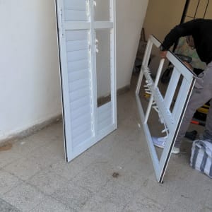 אדם מתקין תריסים לבנים על הרצפה