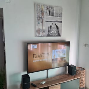 טלוויזיה על קיר עם שלט ושני רמקולים