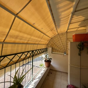 סוכך בד צהוב מתוח על מסגרת מתכת במרפסת