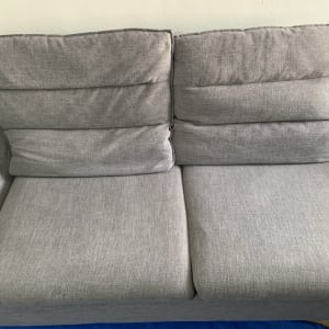 ספה אפורה נקייה על רקע קיר לבן