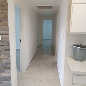 מסדרון דירה ריקה צבועה בלבן אחיד עם משקופים לבנים וחיפוי אבן