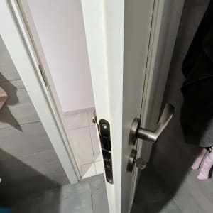 דלת לבנה פתוחה עם ידית מתכת ומנעול