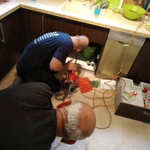 שני אינסטלטורים עובדים מתחת לכיור במטבח