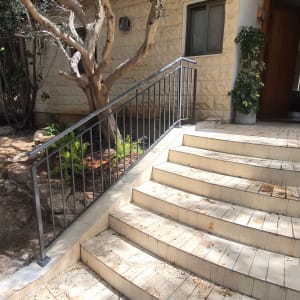 מעקה מתכת לאורך מדרגות חיצוניות לבית