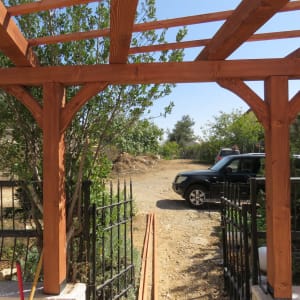 פרגולה מעץ עם גדר מתכת בגינה