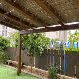 פרגולה מעץ עם גדר עץ ודגלים