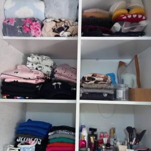 בגדים מקופלים ומוצרי טיפוח על מדפים בארון