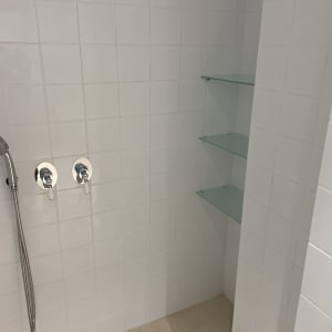 מקלחת עם ראש מקלחת ידני ומדפי זכוכית