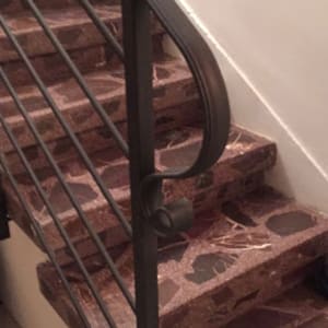 מעקה מתכת שחור על מדרגות שיש חום