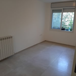 חדר ריק עם רדיאטור, חלון ורצפת אריחים