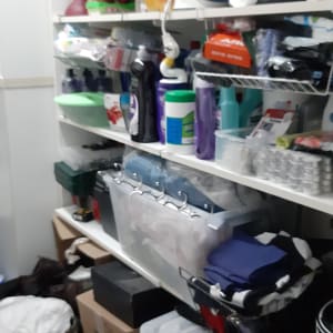 מדפים עם מוצרי ניקוי, מגבות, קופסאות אחסון ושקיות