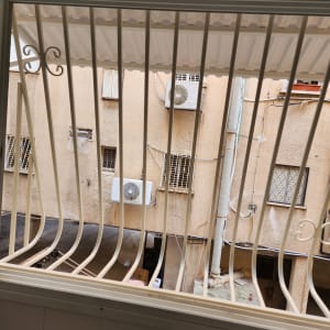 סורגים לבנים על חלון עם נוף לחצר פנימית